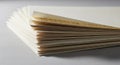 A stack of beige-colored paper sheets lies fanned out on a smooth surface. The papers are slightly Royalty Free Stock Photo