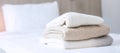 Stack of beige wool Sweaters on bed in luxury hotel or resort or home. Relax, autumn or winter clothes, laundry and vacation