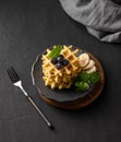 A stack of belgian waffles with kiwi, banana slices and mint, drizzled with honey syrup on a gray plate on a dark background Royalty Free Stock Photo