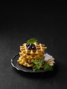 A stack of belgian waffles with kiwi, banana slices and mint, drizzled with honey syrup on a gray plate on a dark background Royalty Free Stock Photo