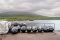 Stack of big buoy for fishing of farming on a pier. Mountains in the background, Cloudy sky. West of Ireland. Fish industry