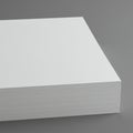 A stack of blank white paper is neatly aligned in a block on a gray background. Royalty Free Stock Photo