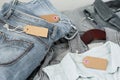 Stack of blue jeans, shirts and empty tag. Second hand clothing shop