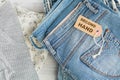 Stack of blue jeans and tag with inscription second hand