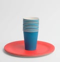 Stack of blue paper cups and red round plates on a white background Royalty Free Stock Photo