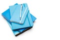 Stack of blue ring binder book and notebook with silver pencil on white background