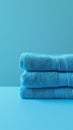 Stack of blue towels on turquoise background, minimalistic composition. Cleanliness and hygiene concept Royalty Free Stock Photo