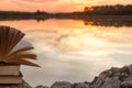 Stack of book and Open hardback book on blurred nature landscape backdrop against sunset sky with back light. Copy space, back to Royalty Free Stock Photo