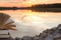 Stack of book and Open hardback book on blurred nature landscape backdrop against sunset sky with back light. Copy space, back to Royalty Free Stock Photo