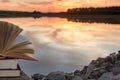 Stack of book and Open hardback book on blurred nature landscape backdrop against sunset sky with back light. Copy space, back to Royalty Free Stock Photo