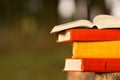 Stack of book and Open hardback book on blurred nature landscape backdrop. Copy space, back to school. Education background.