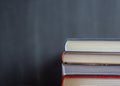 Stack of book resting in front of a chalkboard