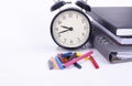 Stack of book with ticking vintage clock and colorful crayon on white table Royalty Free Stock Photo