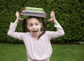 Stack of books balances on the head of a 7 year old girl Royalty Free Stock Photo