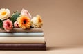 stack of books with beautiful flowers on beige background with copy space