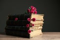 Stack of books and beautiful flowers on table against black background, closeup Royalty Free Stock Photo