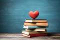 A stack of books and a big red heart on a blue background. Copy space Royalty Free Stock Photo
