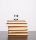 stack of books and a black alarm clock on the table Royalty Free Stock Photo