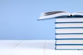 A stack of books on a blue background. One hidden book on top of the pile. Royalty Free Stock Photo