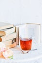 a stack of books, a book and tea in a glass Cup on bright background with branch of Orchid, the concept of love of reading, time t Royalty Free Stock Photo