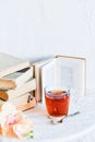 a stack of books, a book and tea in a glass Cup on bright background with branch of Orchid, the concept of love of reading, time t Royalty Free Stock Photo