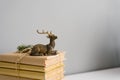 A stack of books in crane paper and a statuette of a sitting deer on a gray background