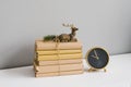 A stack of books in crane paper, tied with twine, they is a statuette of a sitting deer