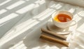Stack of books with a cup of tea on a light gray table, soft shadows from window Royalty Free Stock Photo