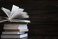 Stack of books with dark wooden background. One book is opened. Royalty Free Stock Photo