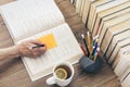 Stack of books education background, female hand makes notes near open textbook. Glasses, pens and pencils in holder, cup of tea Royalty Free Stock Photo