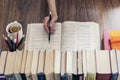 Stack of books education background, female hand makes notes near open textbook. Glasses, pens and pencils in holder, cup of tea Royalty Free Stock Photo