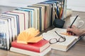 Stack of books education background, female hand makes notes near open textbook. Glasses, pens and pencils in holder, cup of tea Royalty Free Stock Photo