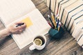 Stack of books education background, open book, female hand with pencil, glasses, and cup of tea with lemon Royalty Free Stock Photo