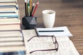 Stack of books education background, open textbook and notebook, glasses, pens and pencils in holder, cup of tea with lemon