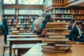 Stack of books in foreground with students studying in the blurred library background Royalty Free Stock Photo
