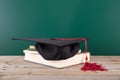 A stack of books in front of the blackboard and a doctor hat on the books Royalty Free Stock Photo