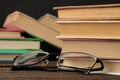 A stack of books and glasses on a brown wooden table and on a black background. Old books. Education. school. Royalty Free Stock Photo