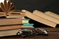 A stack of books and glasses on a brown wooden table and on a black background. Old books. Education. school. Royalty Free Stock Photo