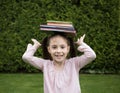 Stack of books on the head of a cheerful girl 7 years old. back to school concept Royalty Free Stock Photo