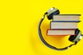 Stack of books with headphones on a yellow background