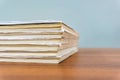 A stack of books are lying on a brown table, documents are stacked close-up