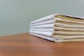 A stack of books are lying on a brown table, documents are stacked close-up