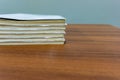 A stack of books are lying on a brown table, documents are stacked close-up