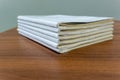 A stack of books are lying on a brown table, documents are stacked close-up