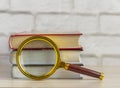 A stack of books and a magnifying glass on the table.The concept of information retrieval