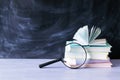 Stack of books, magnifying glass on table, learning concept