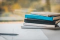 Stack of Books in Front of Window Next to Pen and Paper Royalty Free Stock Photo