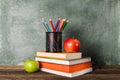 A stack of books and office supplies and two apples on the background of the school board. Royalty Free Stock Photo