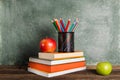 A stack of books and office supplies and two apples on the background of the school board. Royalty Free Stock Photo