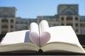 Stack of books oin the window with city view with top one opened and pages forming heart shape. Royalty Free Stock Photo